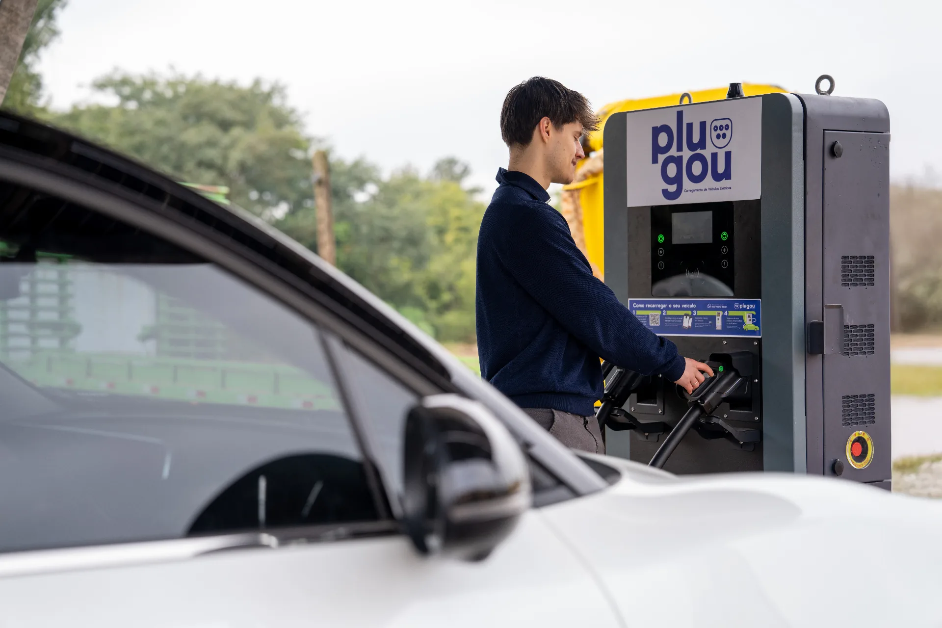 Motorista conectando cabo em veículo elétrico na estação Plugou